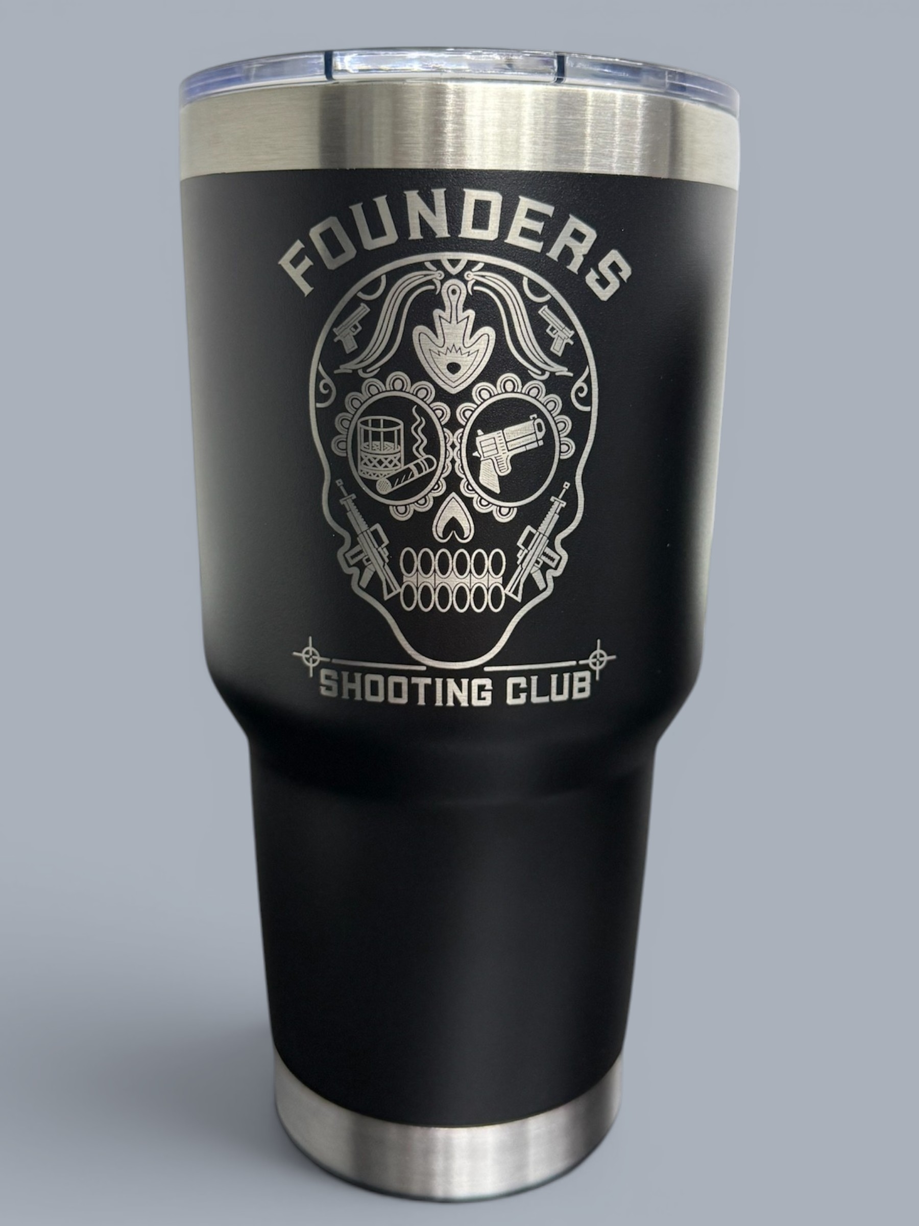 A black tumbler with a silver skull design and the text "FOUNDERS SHOOTING CLUB" on the front, featuring a clear lid and stainless steel base.