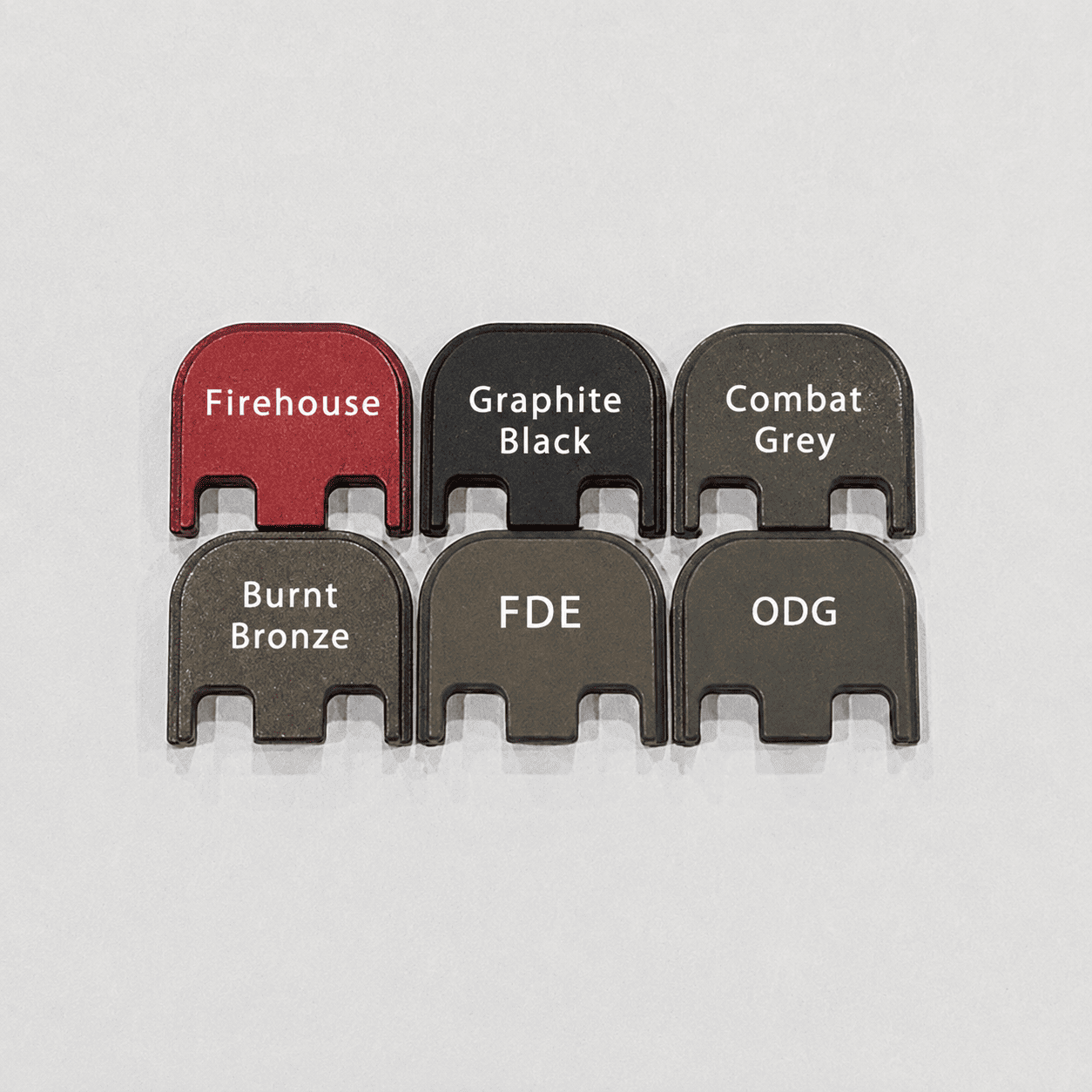 Six metal tabs labeled Firehouse, Graphite Black, Combat Grey, Burnt Bronze, FDE, and ODG, displayed on a light surface, showing different color finishes.